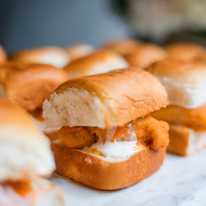 Close-up of a buffalo chicken slider on a marble surface with a blurred background