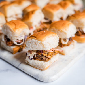 Platter of mini pulled pork sliders on marble surface