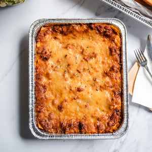 Aluminum pan of lasagna on a marble surface with floral decorations